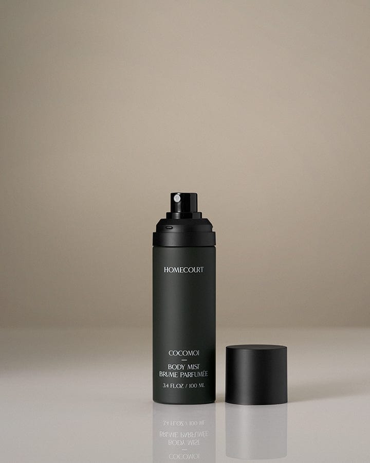 Homecourt Award-Winning body mist Black spray bottle with the cap off on a beige background.
