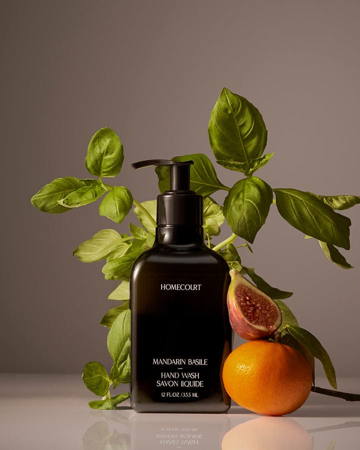 Black pump bottle of award-winning Homecourt Mandarin Basil Hand Wash with mandarin oranges and basil branches around it.