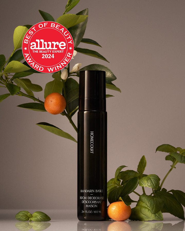 Best of Beauty Allure Award Winner Homecourt Room Deodorizer Mandarine Fragrance next to branches and mandarin fruit.