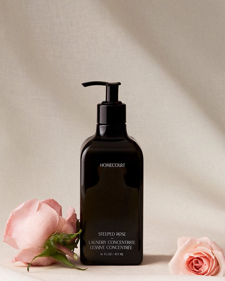 Black bottle of Homecourt plant-based 10X Laundry Concentrate with roses on a beige background.