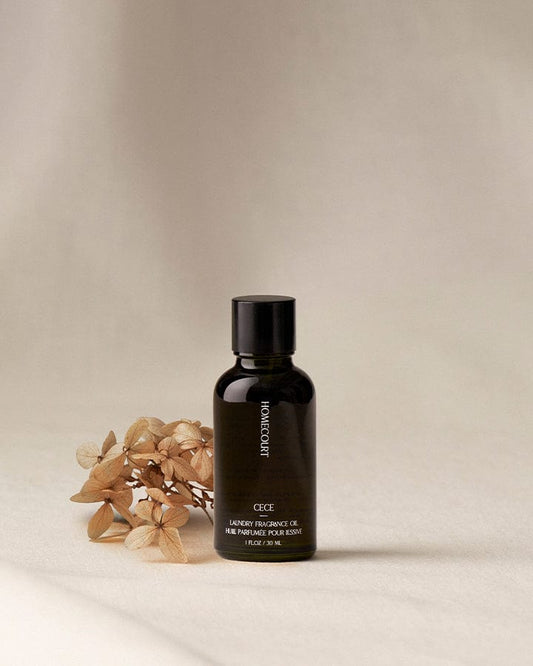 Black bottle of Cece Scented Fragrance Refill for Dryer Balls on a beige background with dried flowers.