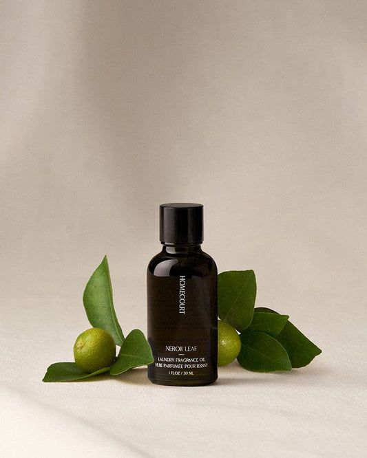 Black bottle of Neroli Scented Fragrance Refill for Dryer Balls on a beige background with Neroli fruit and leaves.