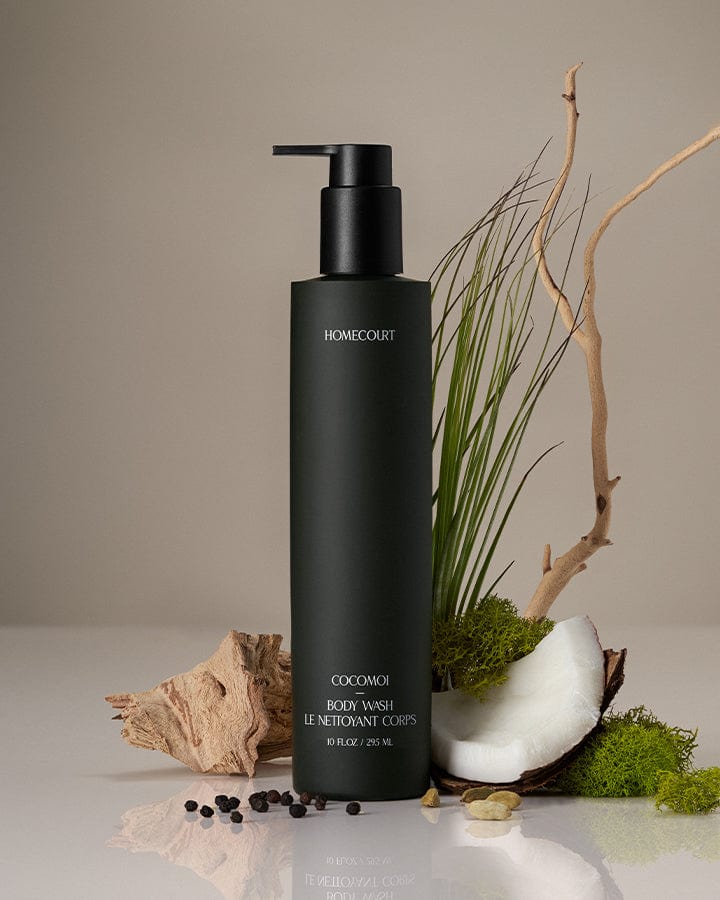 Black bottle of Homecourt coconut body wash with natural elements on a neutral background.