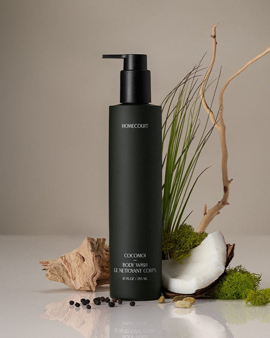Black bottle of Homecourt coconut body wash with natural elements on a neutral background.