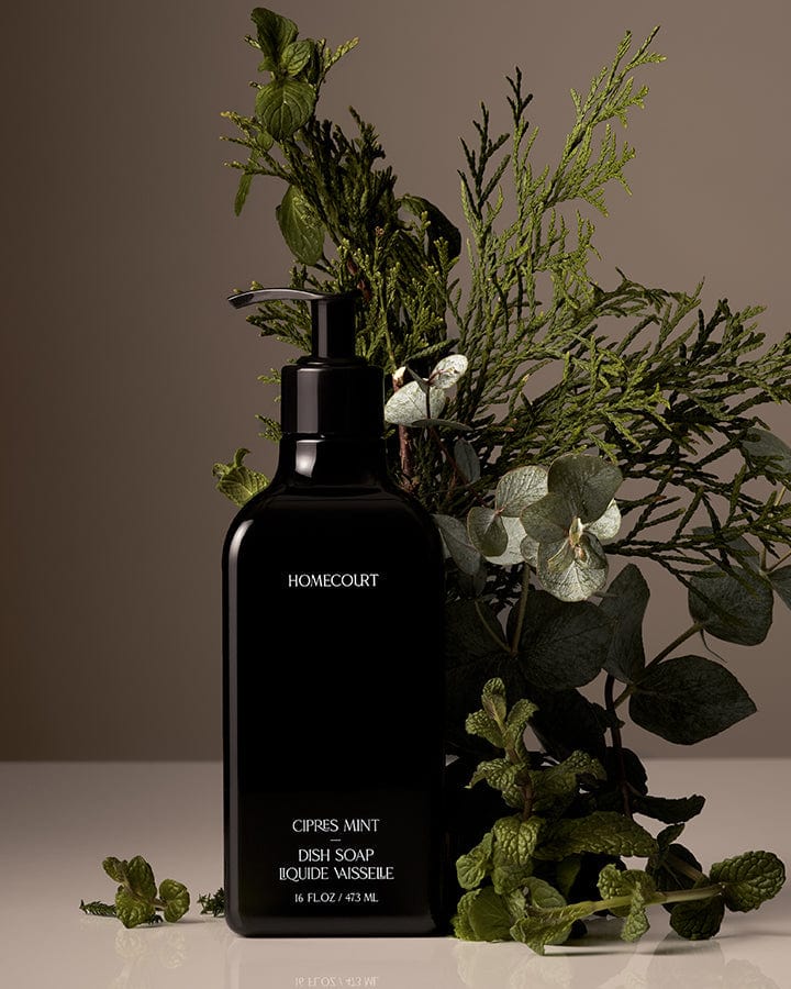Black bottle of Homecourt Award-Winning Dish Soap with greenery on a neutral background.