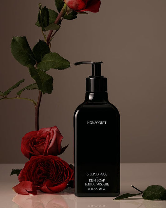 Black bottle of Homecourt Award-Winning Dish Soap with red roses on a neutral background.