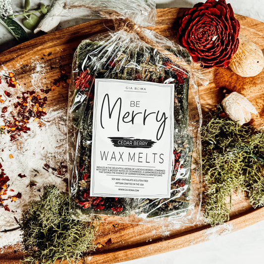 Packaged XL wax melts labeled 'Be Merry Cedar Berry' on a rustic wooden surface with decorative elements.