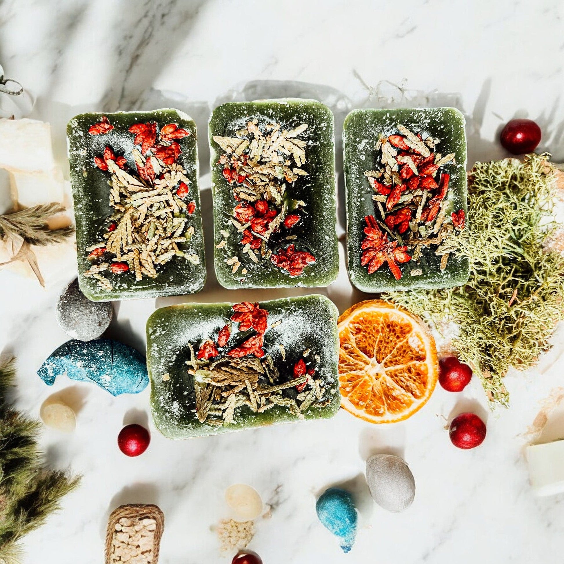 Three Cedar Berry XL wax cubes with dried herbs on a marble surface with decorative elements.