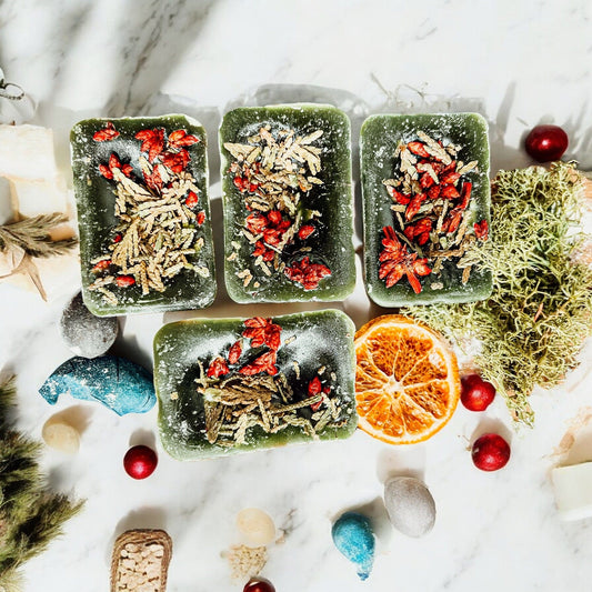 Three Cedar Berry XL wax cubes with dried herbs on a marble surface with decorative elements.