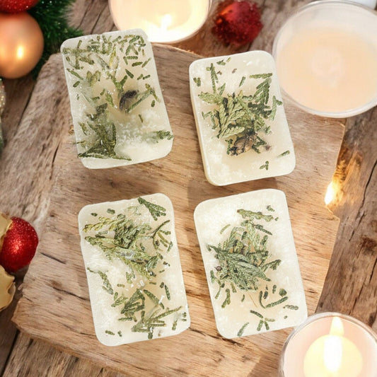 Four rectangular white Christmas Tree XL wax melts with herbs on a wooden surface with candles and Christmas decorations.