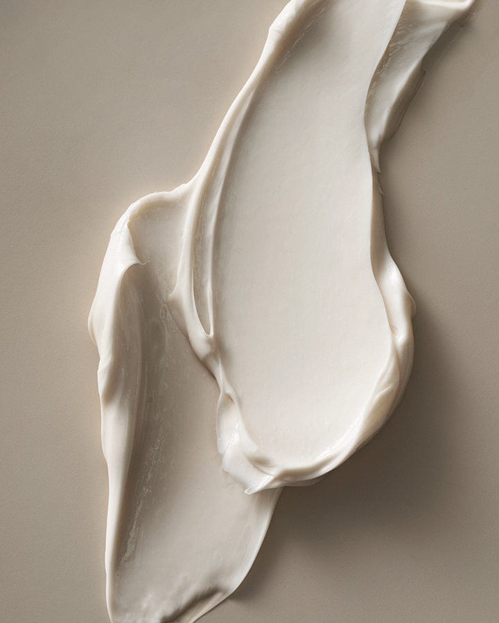 Close-up of Homecourt Indulgent Body Butter - a smooth, white cream swatch on a beige background.