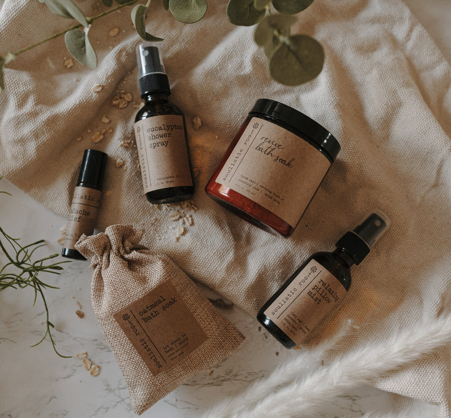 5-Piece Therapeutic Spa Gift Set of natural products with labels on a linen surface with herbs.