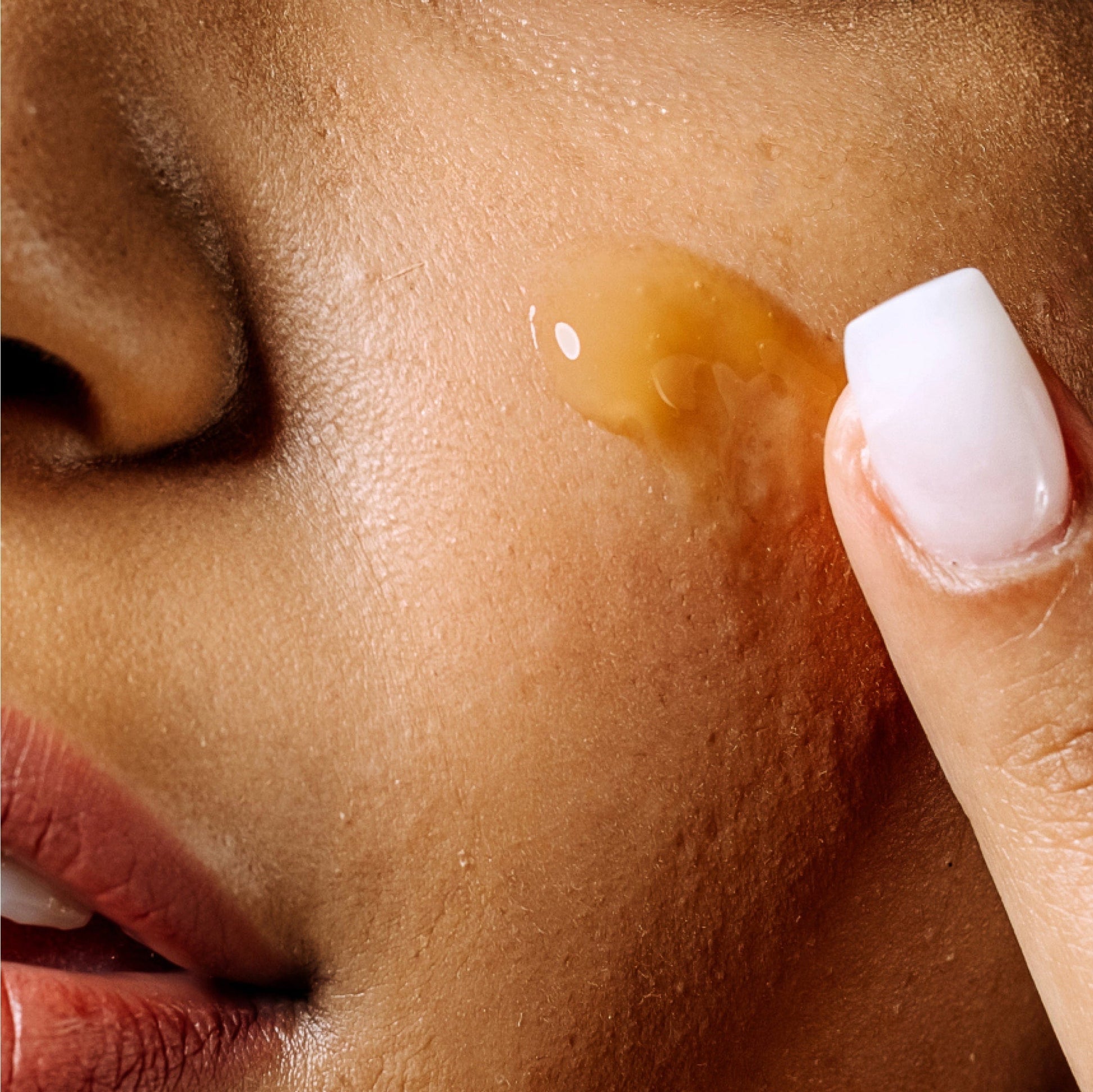 Close-up of a person applying Vitamin C+E Ferulic Serum to their skin with a finger.