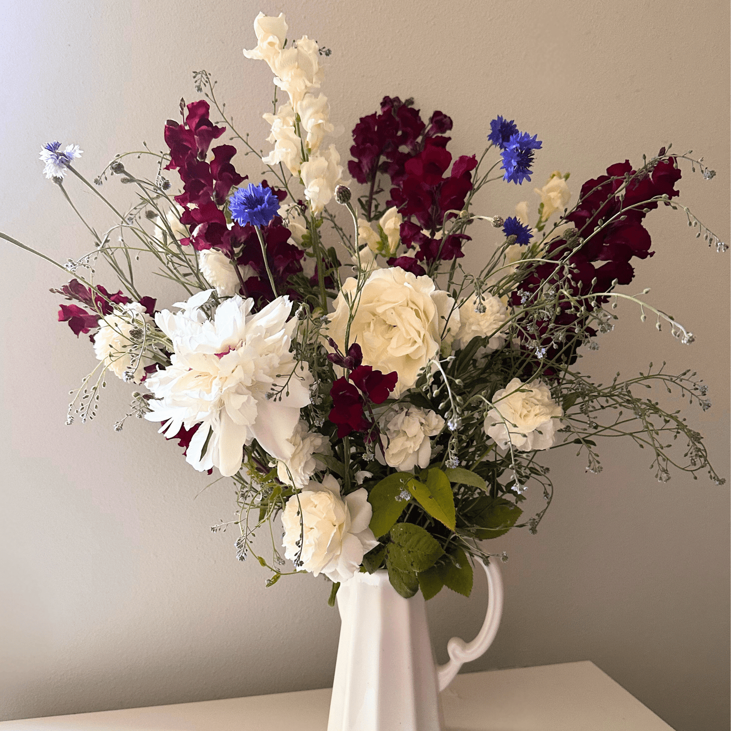 A 4th of July display of Peonies, roses, snapdragons, and blue bachelor button grown & arranged by Little Mountain Flowers